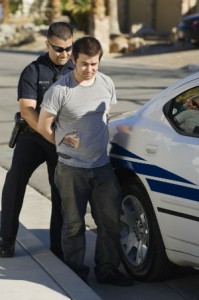 Police Man Arresting A Young Man In Front Of Car